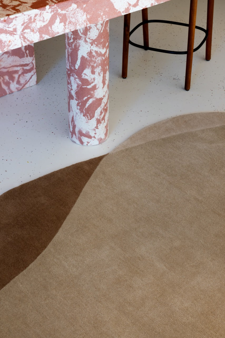 Abstract design rug placed under a dining table with oak chairs

