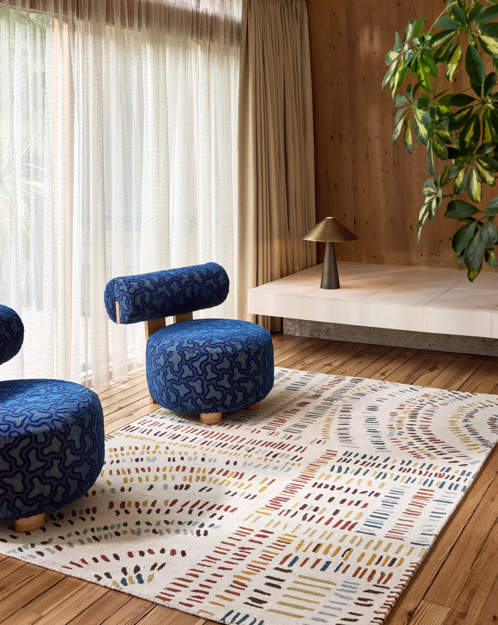 Tapis Harlequin Frescoes Amber ivoire aux traits ambre, rouille et bleu canard, dans un intérieur