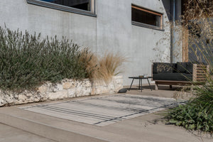 Zona Line Charcoal rug styled under outdoor dining set on a wooden deck